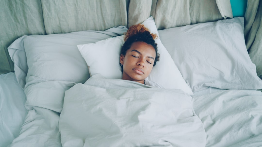 A young woman sleeping peacefully in a white bed.